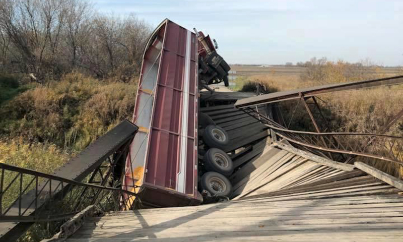 Trucker able to climb out of rig after wooden bridge collapsed
